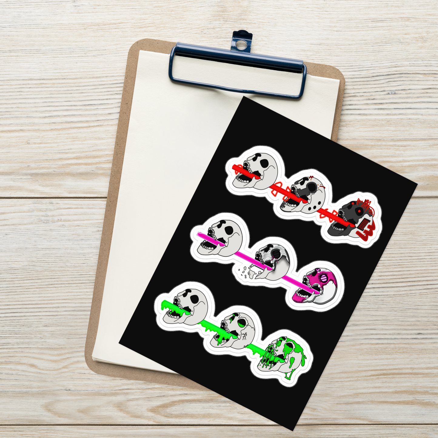 Set of three sticker designs featuring cyberpunk and horror themed skulls shooting different colored lasers on a black background, placed on a clipboard.