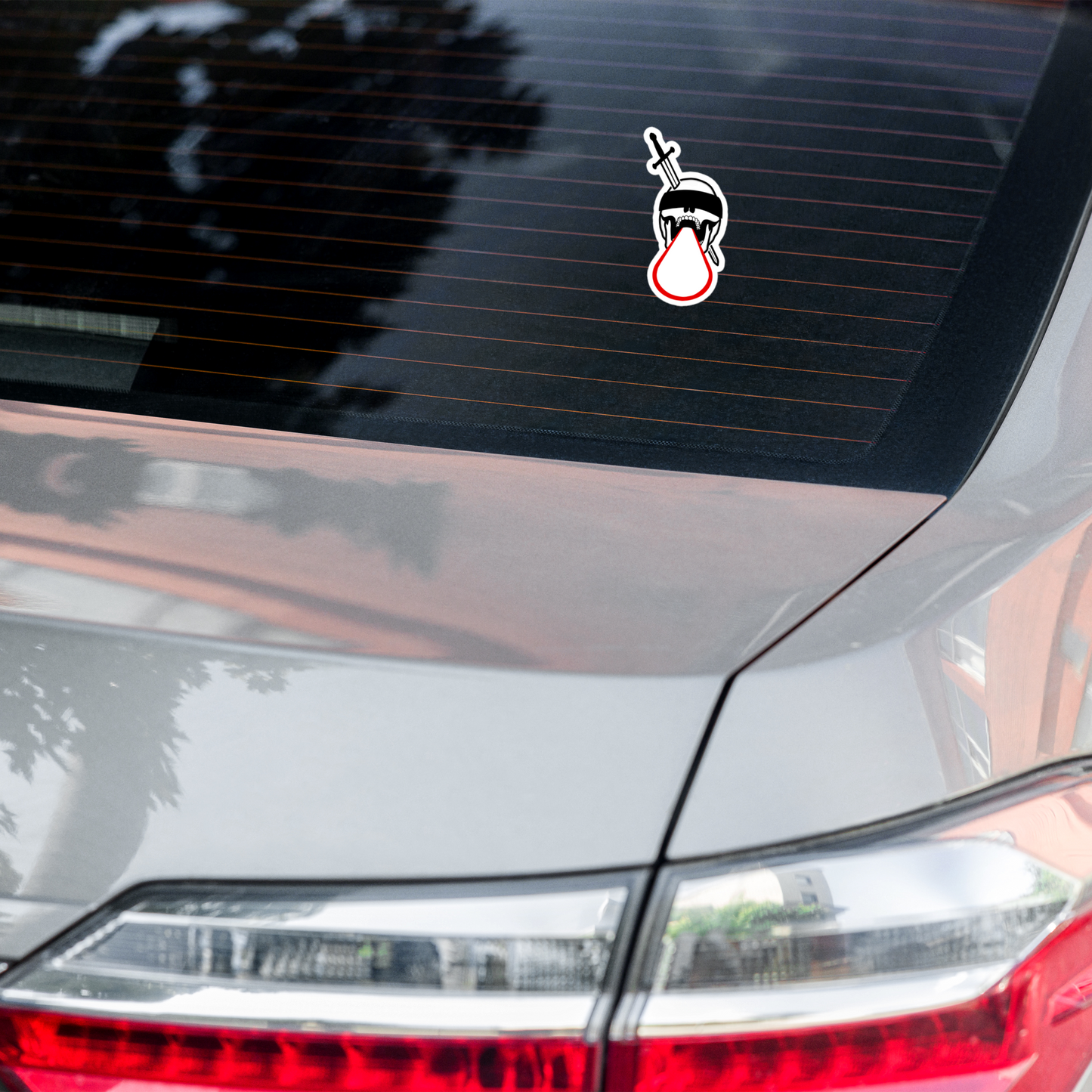 Car sticker on a car's rear window with a design of a character holding a sword.
