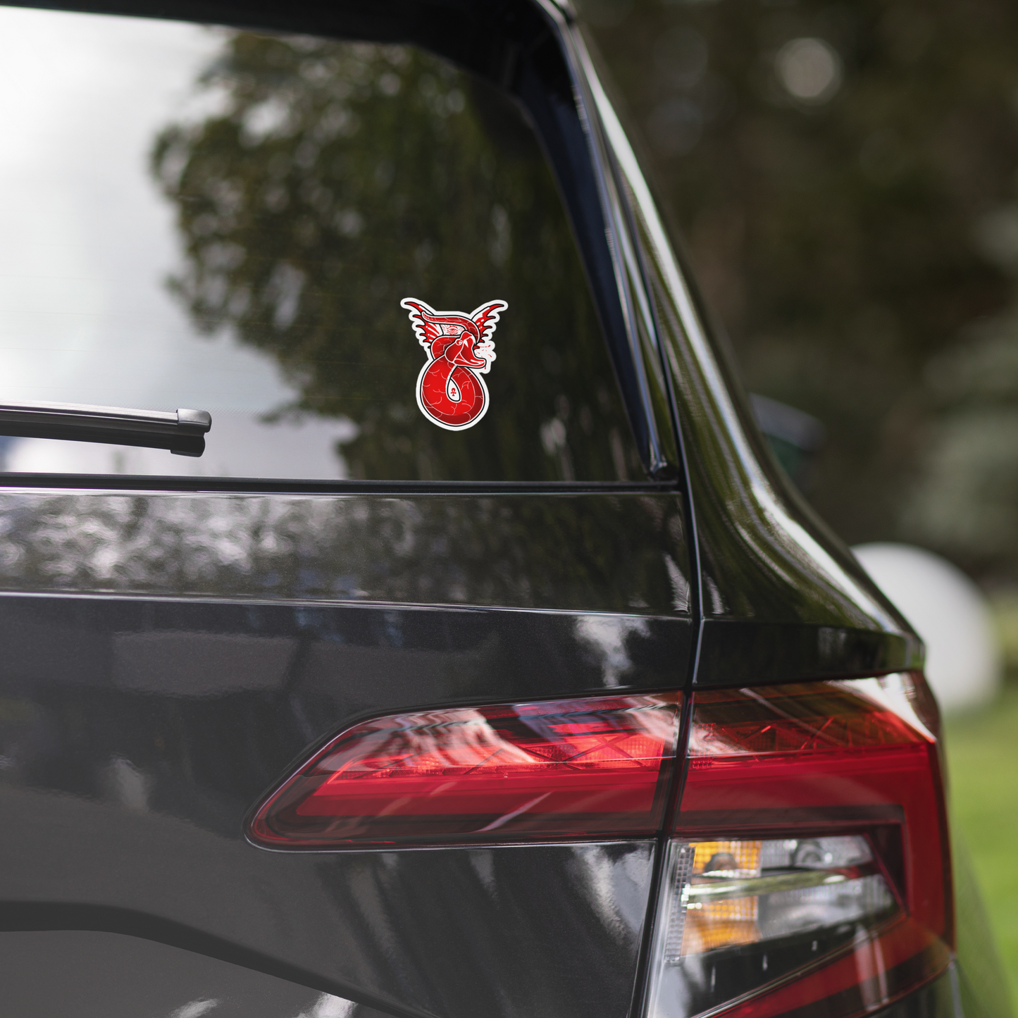 Red snake decal on a car's rear window with a blurred natural background