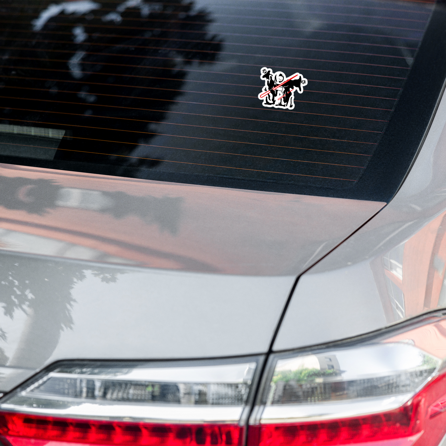 Car sticker on a car's rear window with a design of neorebellion mascot rob being pierced by a red laser on a white background