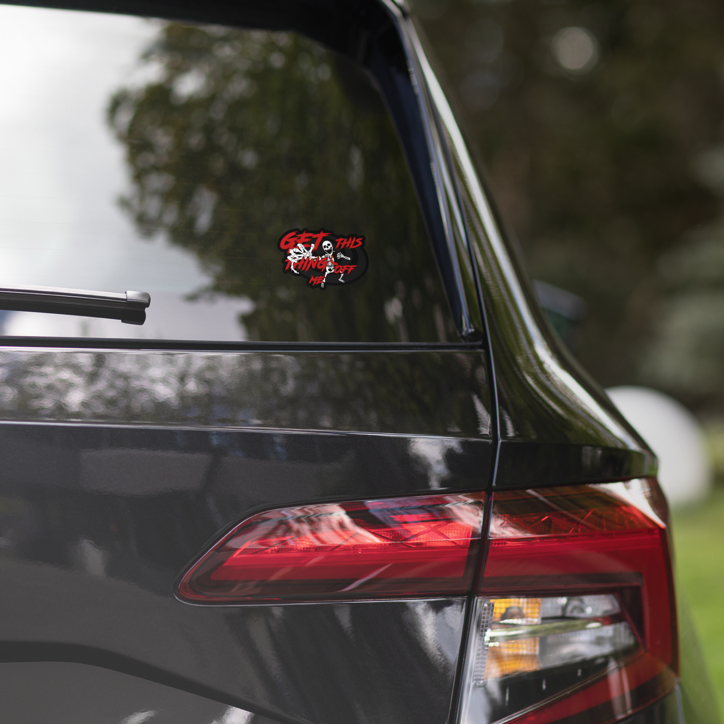 Car rear with a sticker on the window, blurred greenery in the background