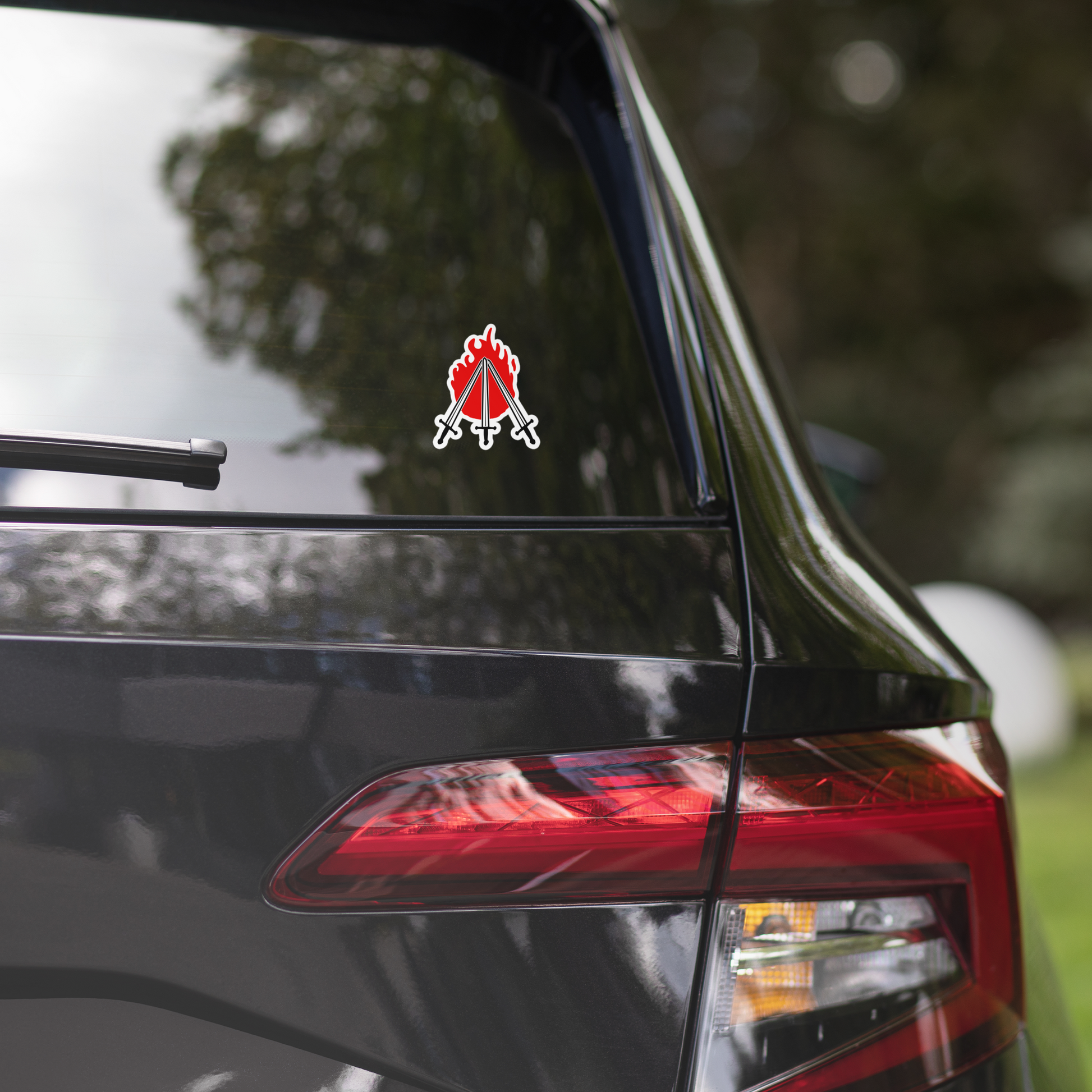 Car with a sticker of three swords crossing in front of red flame on the rear window, featuring a red and white design.