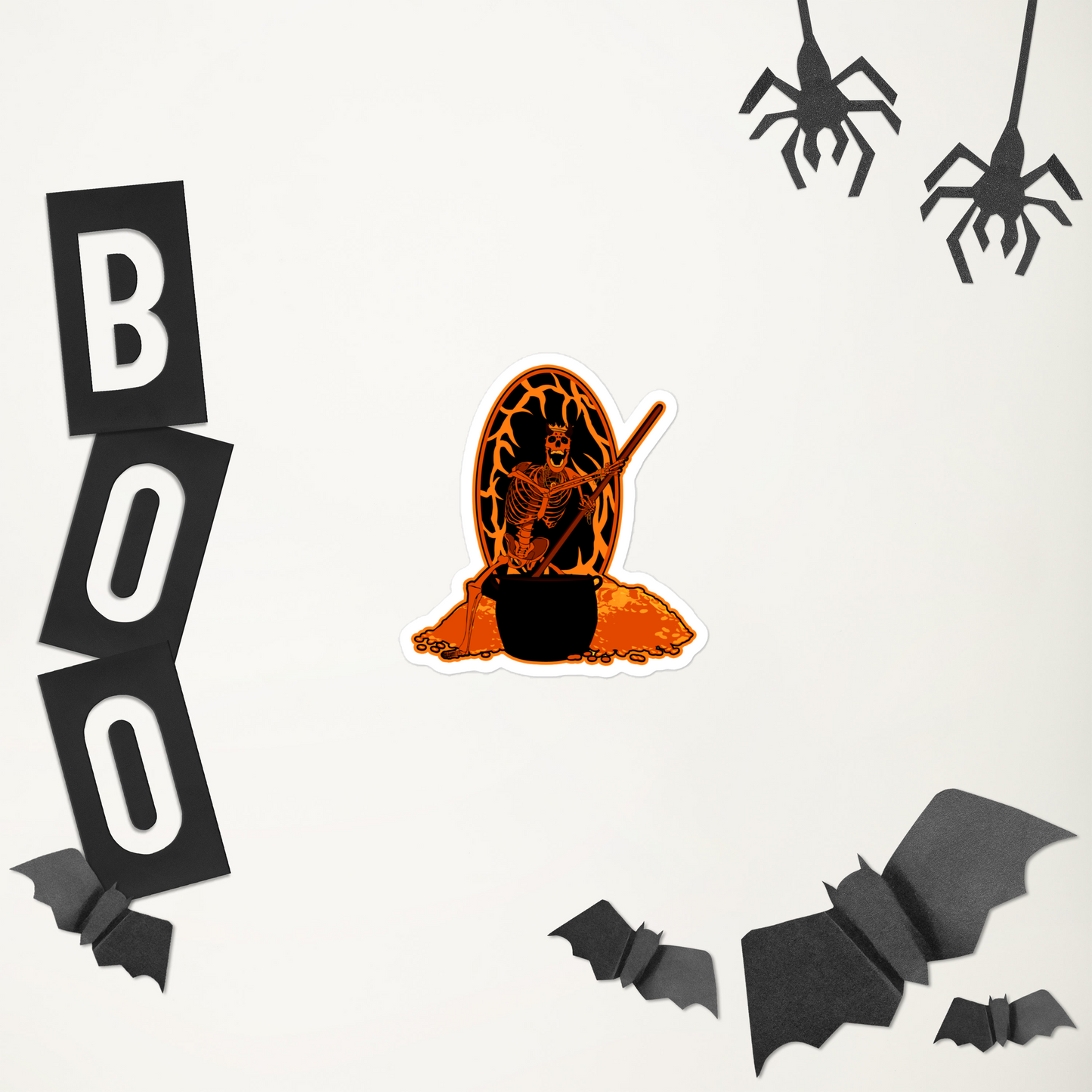 A skeletal figure with a staff and cauldron on an orange and black background sticker in front of Halloween-themed decorations including a pumpkin, 'BOO' letters, bats, and spiders on a white background.