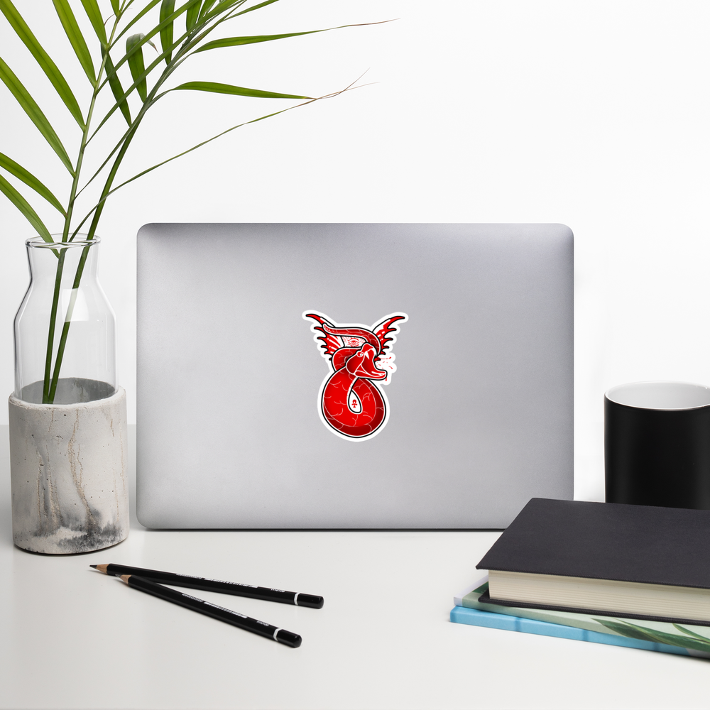 Laptop with a red snake sticker on a white surface with a plant, pencils, and books.