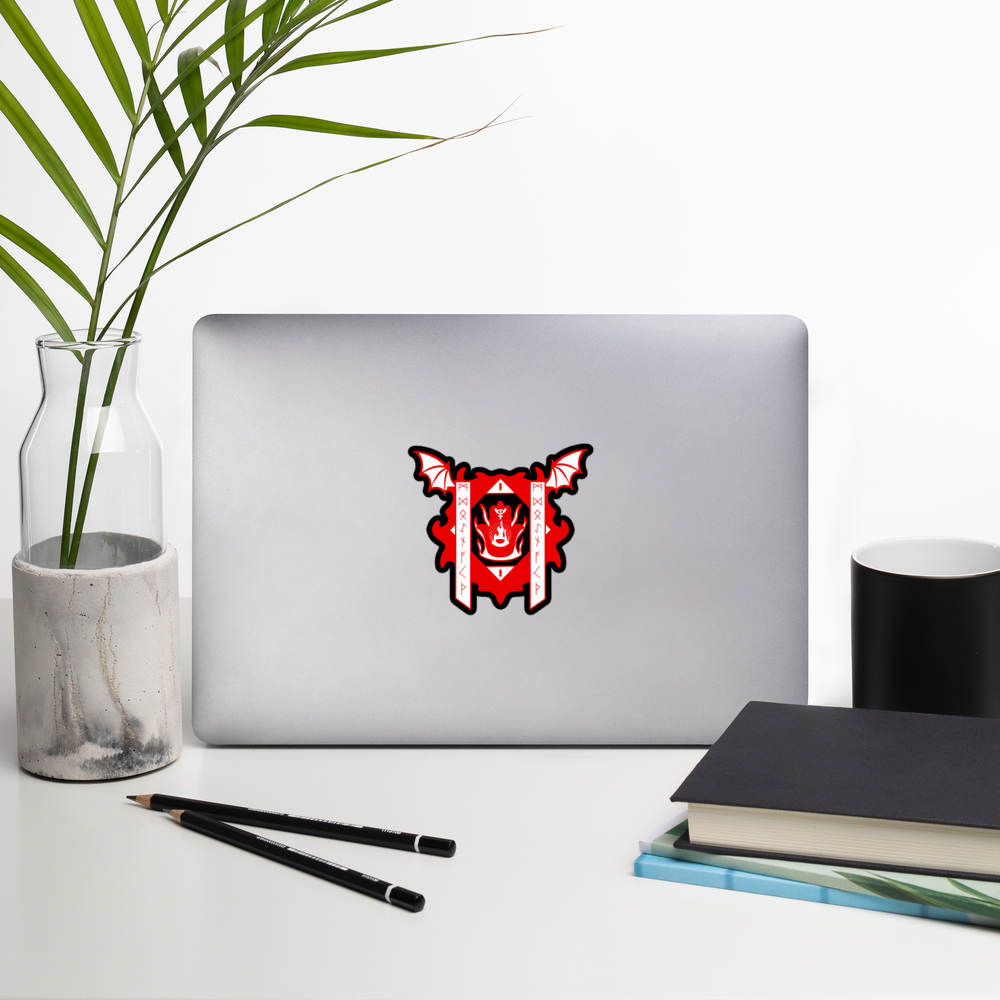 Laptop with a red and black logo on a white surface with a plant, pencils, and books.