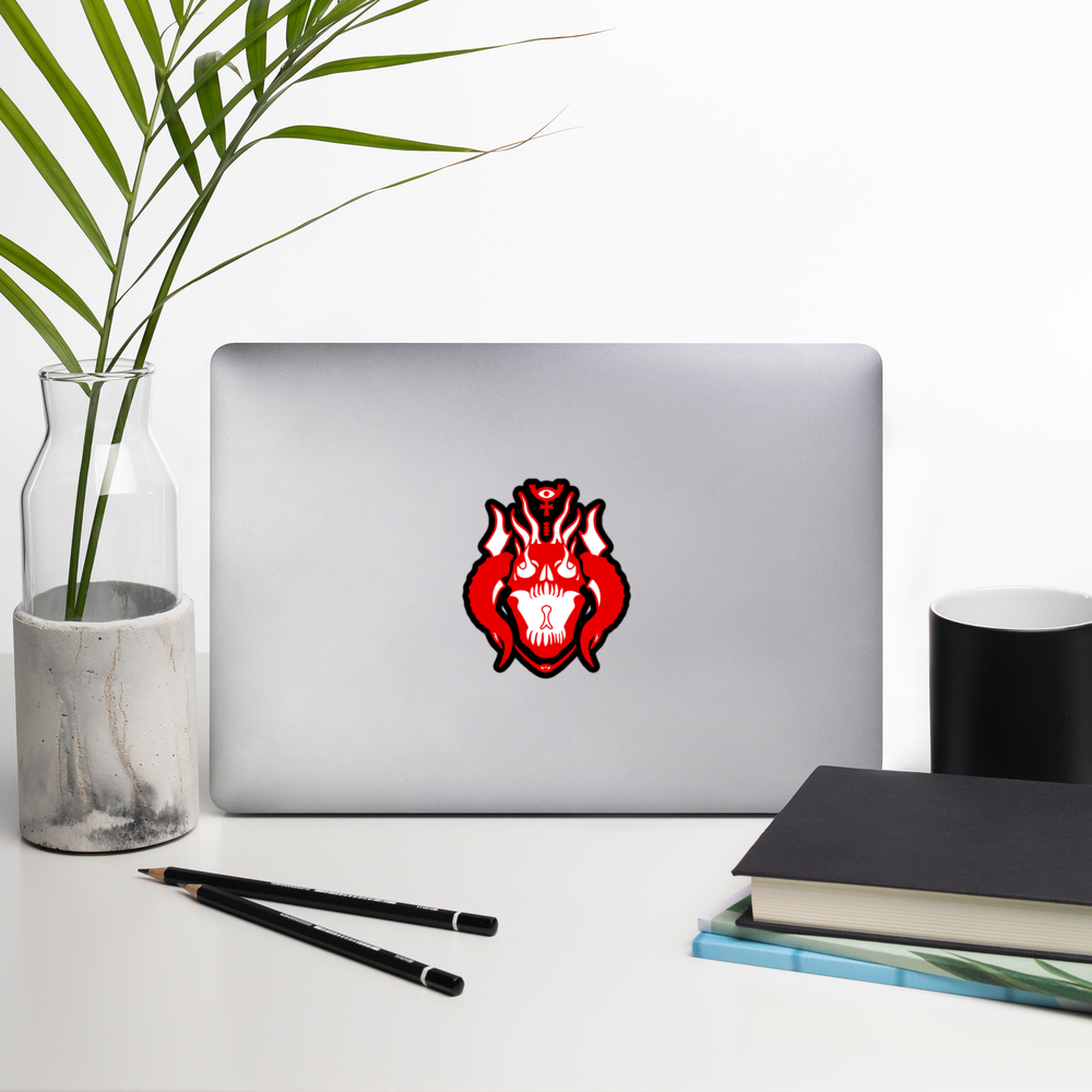 Laptop with a red and black emblem on a white surface with a plant, pencils, and books.