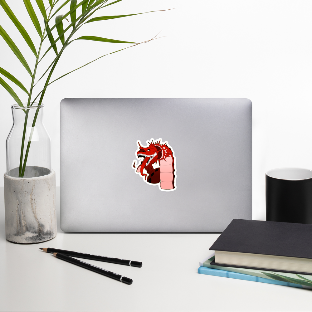 red chinese dragon sticker on the back of a laptop by some office supplies and a plant