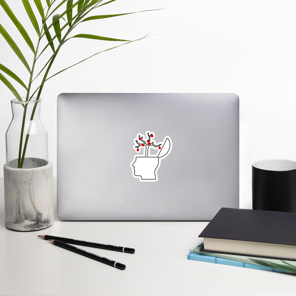 Laptop with a branching mind academia style sticker on a desk with a plant, pencils, and books.