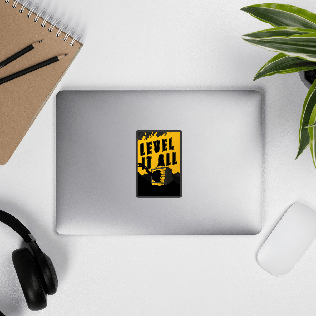 Laptop with a 'Level It All' sticker on a desk with a notebook, pens, and headphones.
