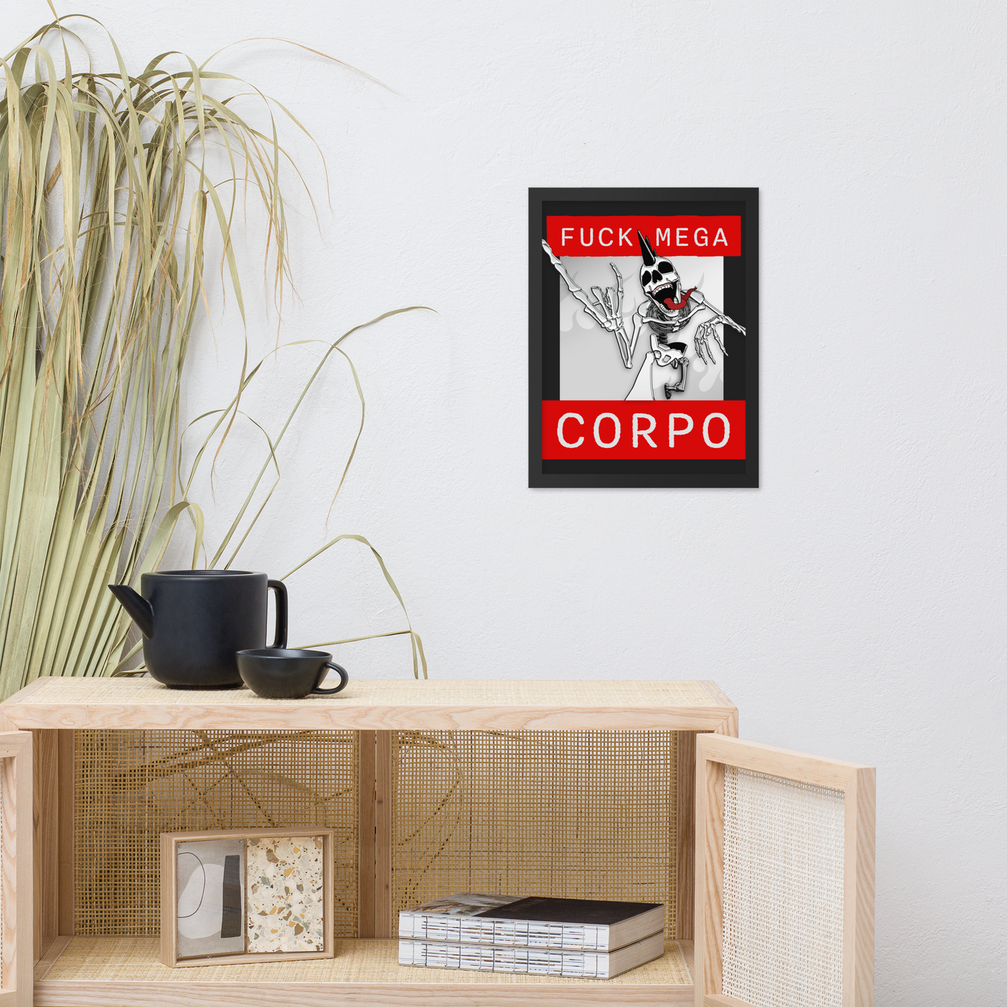 Framed artwork of a heavy metal skeleton in front of 'FUCK MEGA CORPO' text with red, white, black, and grey coloration above a wooden shelf with decor items.