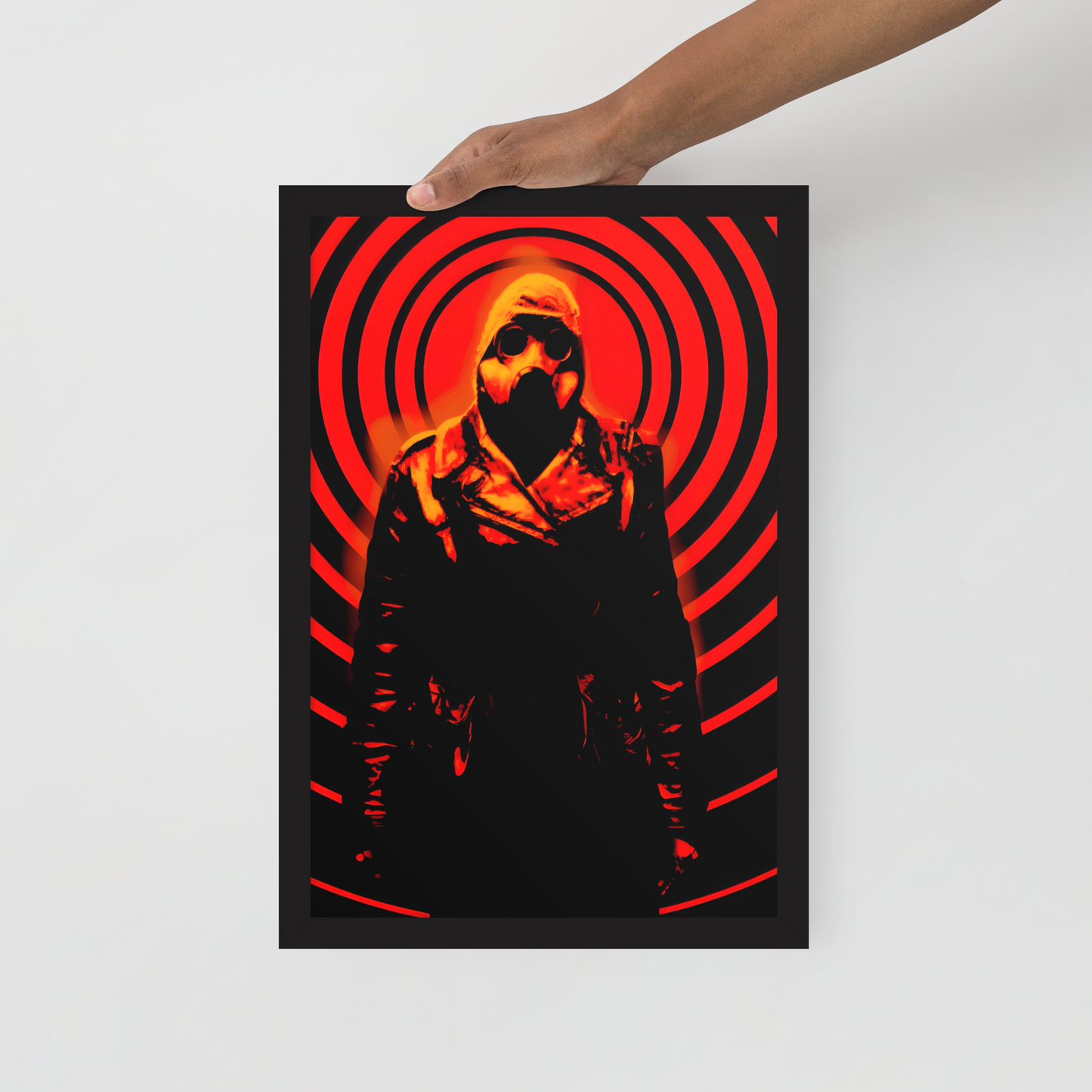 Person holding a 12x18 poster with a mysterious figure in a dark outfit with a hood and a gas mask against an orange and black circular background.