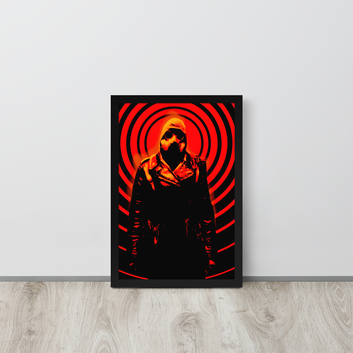 Framed artwork of a a mysterious figure in a dark outfit with a hood and a gas mask against an orange and black circular background on a white wall.