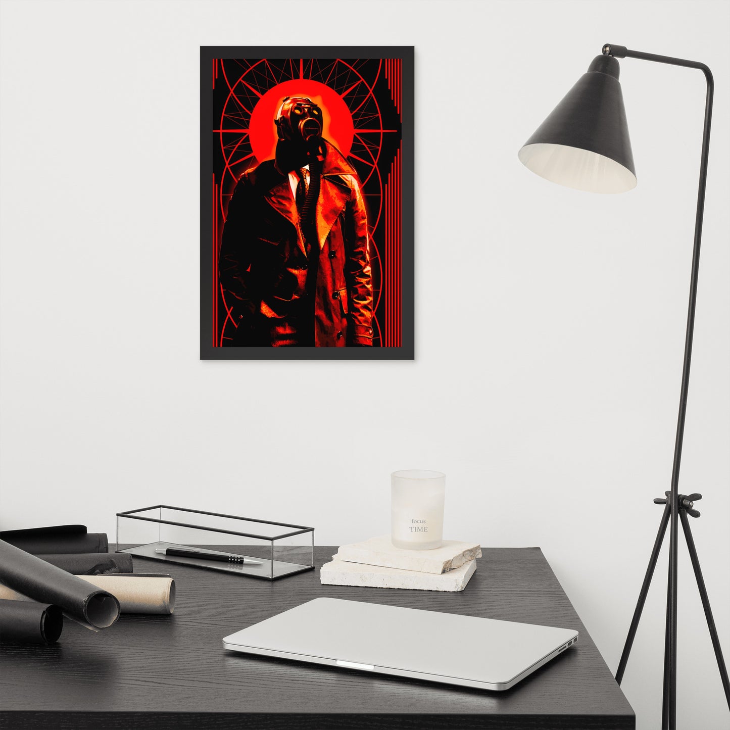 Framed 12x18 artwork of a stylized, art-deco style illustration in orange, black, and white tones, with a mysterious figure in a gas mask and a trench coat in the center on a wall above a desk with a laptop and decor items.