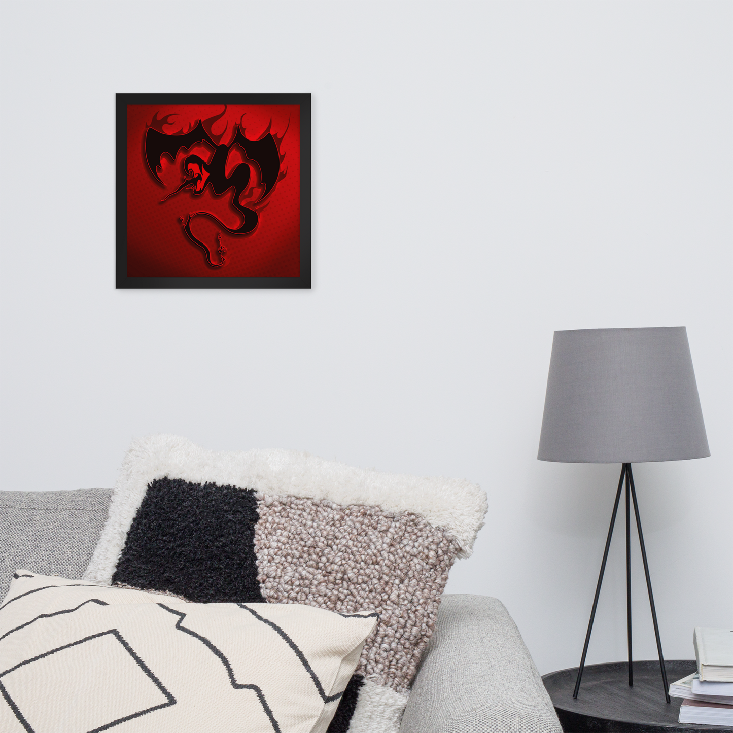 Framed artwork with a red background and black design on a wall above a sofa with decorative pillows.