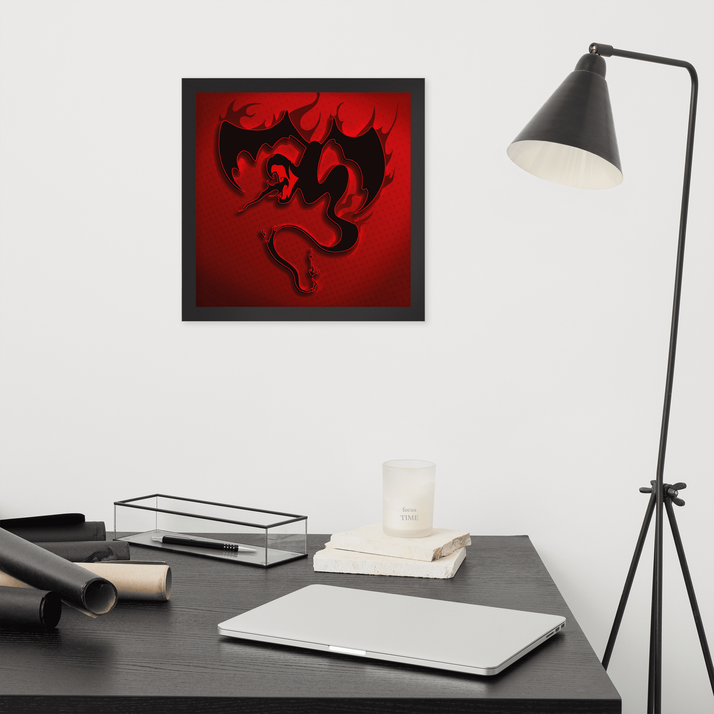 Framed artwork of a dragon on a red background above a desk with a laptop and lamp.