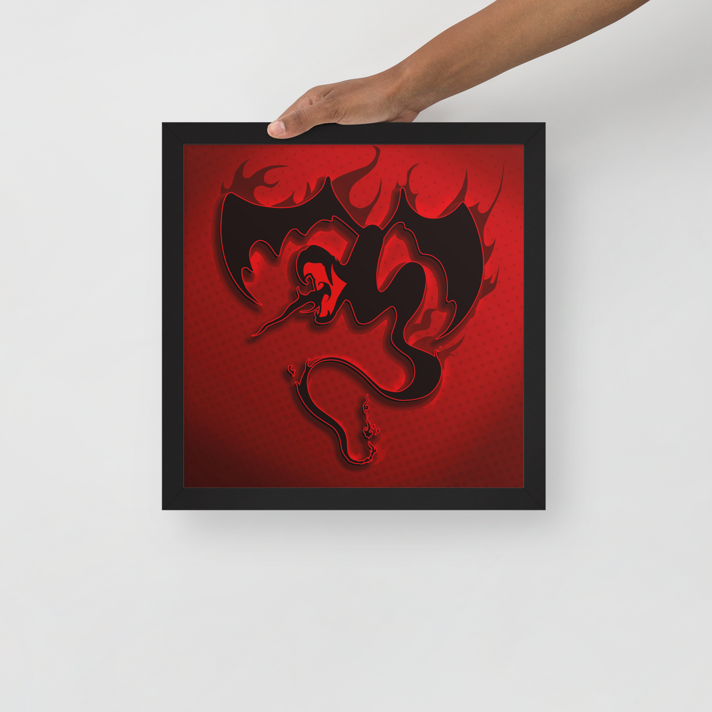 Framed artwork with a red and black dragon design held by a hand on a white background