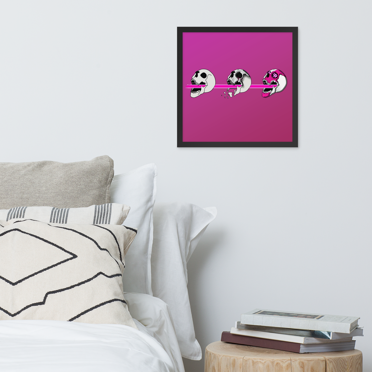 Framed 16x16 artwork of a pink background and black frame, featuring three stylized cyberpunk skull designs shooting a laser with purple and black details with abstract design on a wall above a bed.