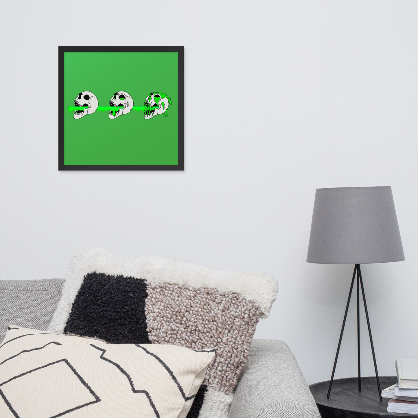 Framed artwork of 3 skulls shooting green slime from their mouths with a gradient background in a horror style in a living room setting.