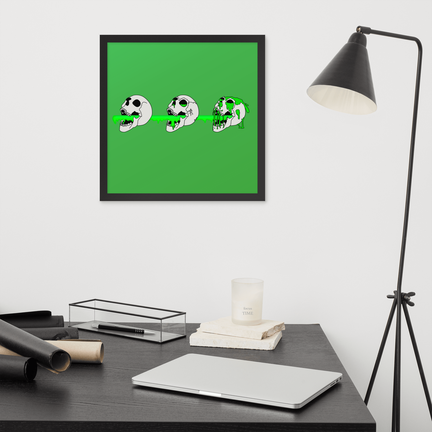 Framed artwork of a 16x16 3 skulls shooting green slime from their mouths with a gradient background in a horror style , displayed above a desk.