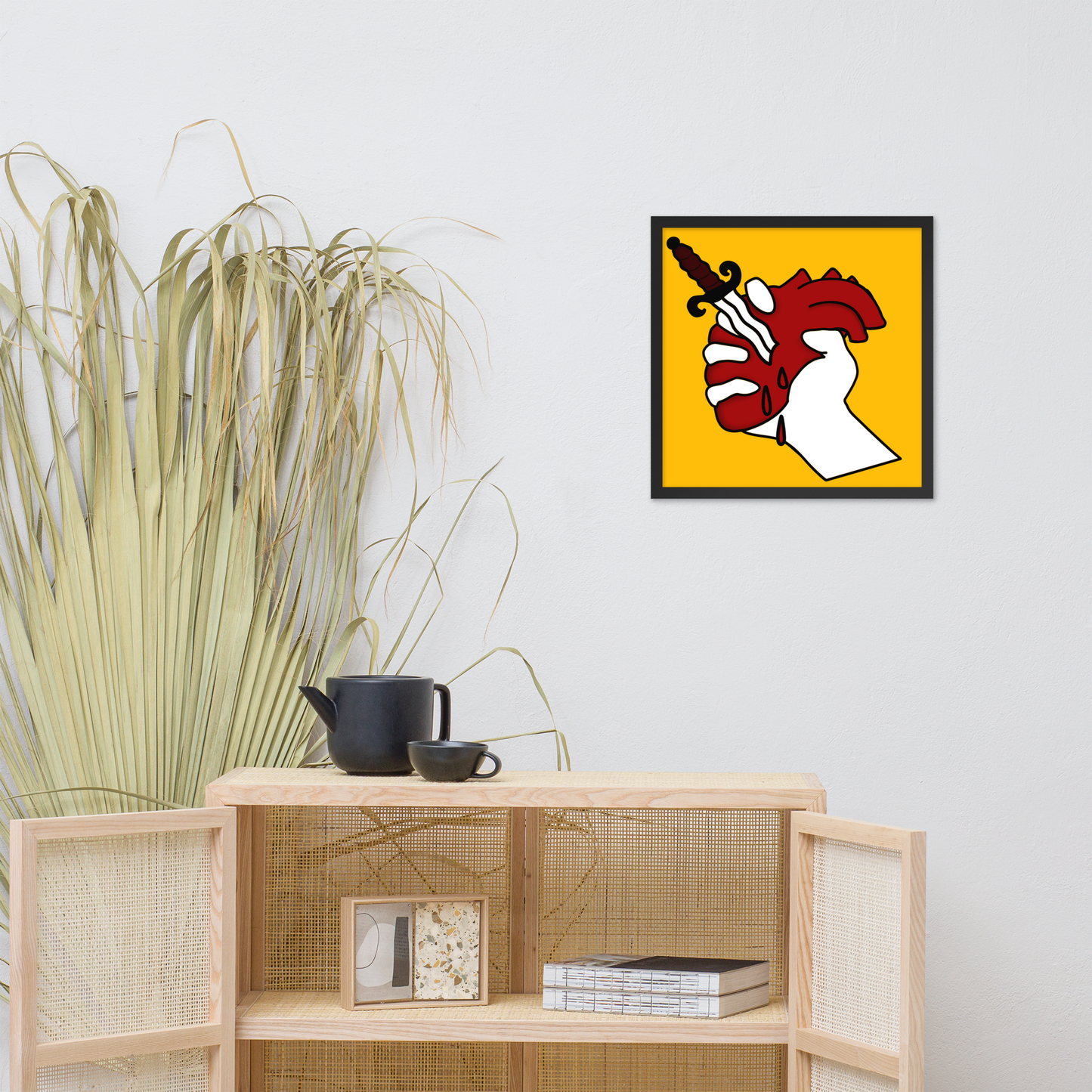Framed artwork on a wall above a wooden cabinet with decorative items.