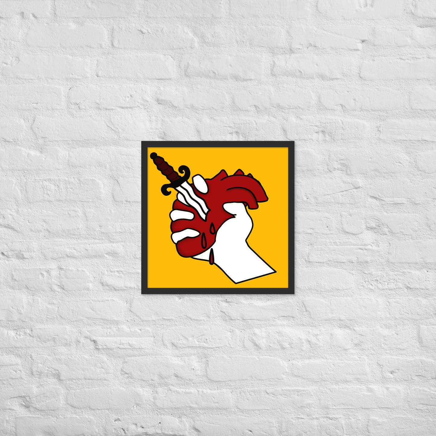 Framed artwork of a hand holding a heart with a dagger on a yellow background, mounted on a textured white wall.