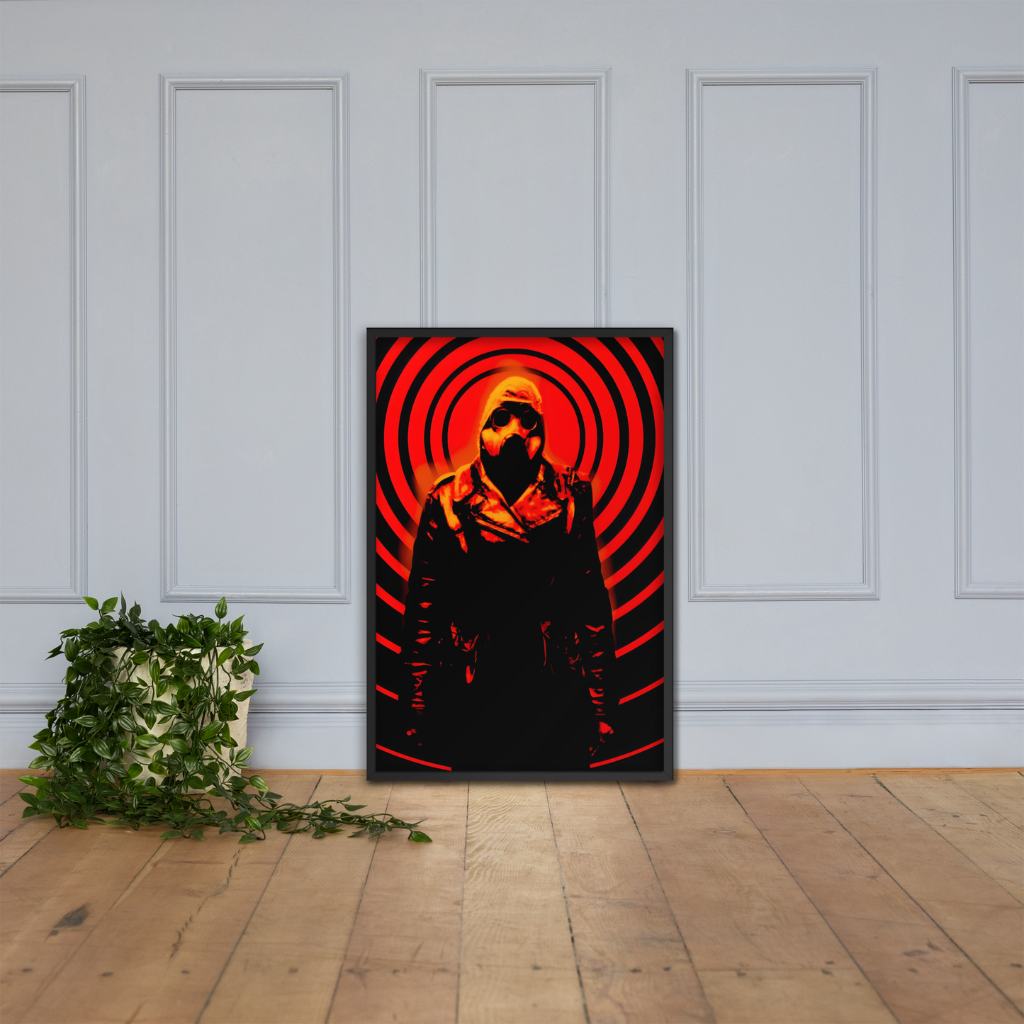 24x36 framed artwork of a mysterious figure in a dark outfit with a hood and a gas mask against an orange and black circular background on a white paneled wall.