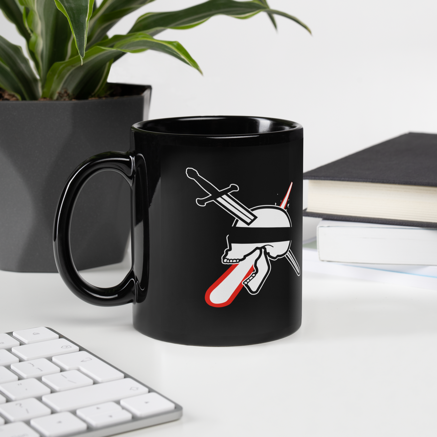 Black mug with a graphic design on a desk with a keyboard and plant