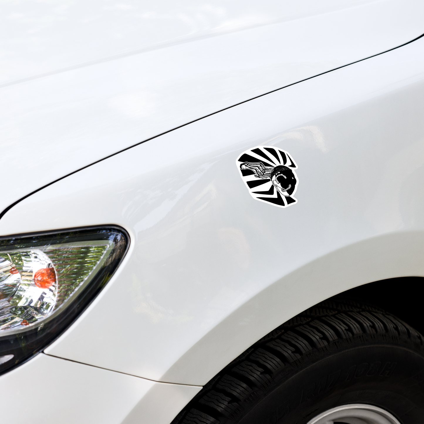 Car with a black and white graphic of a skeleton hand reaching upwards to pull thorns from his face in front of a sharp pattern in the background decal on the hood