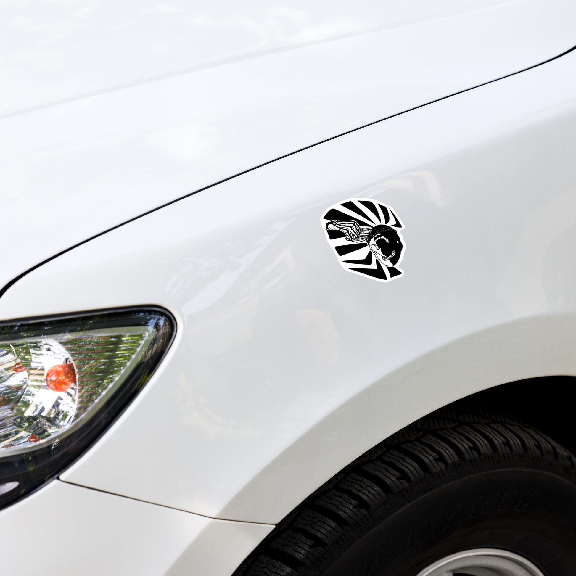 Car with a black and white graphic of a skeleton hand reaching upwards to pull thorns from his face in front of a sharp pattern in the background decal on the hood