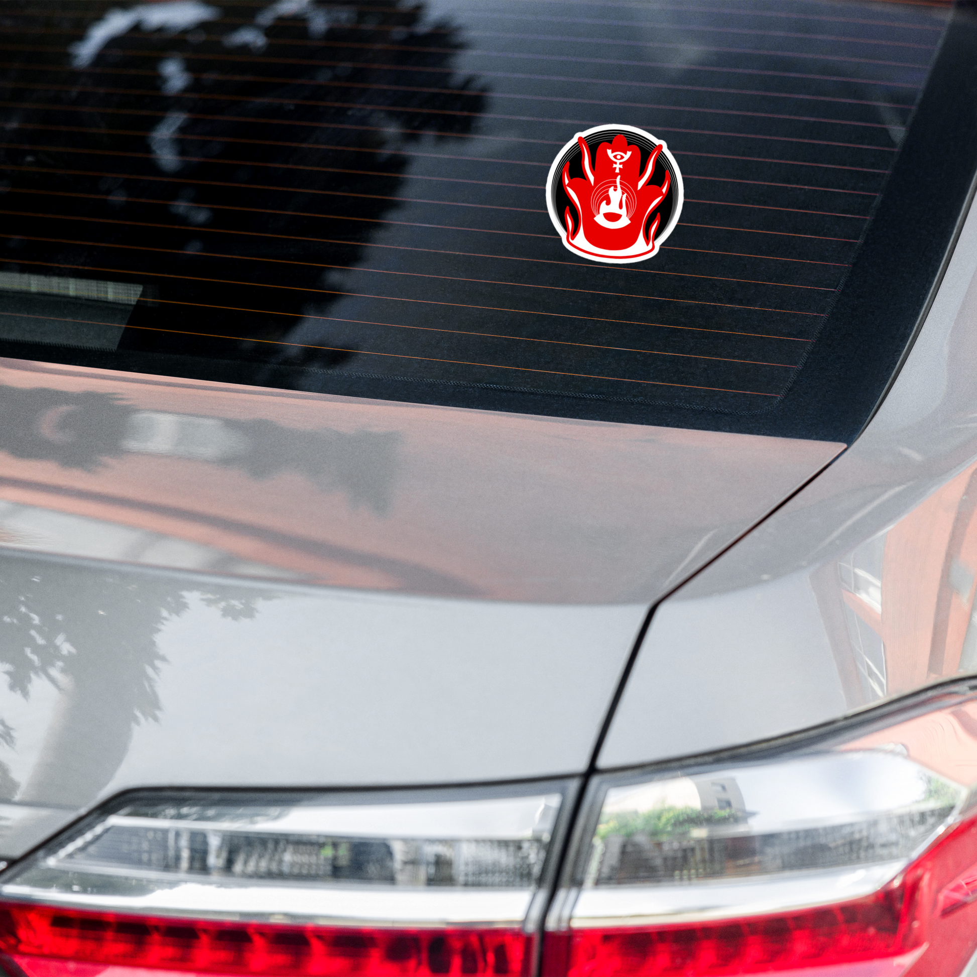Car sticker with a red and white design on a car's rear window.