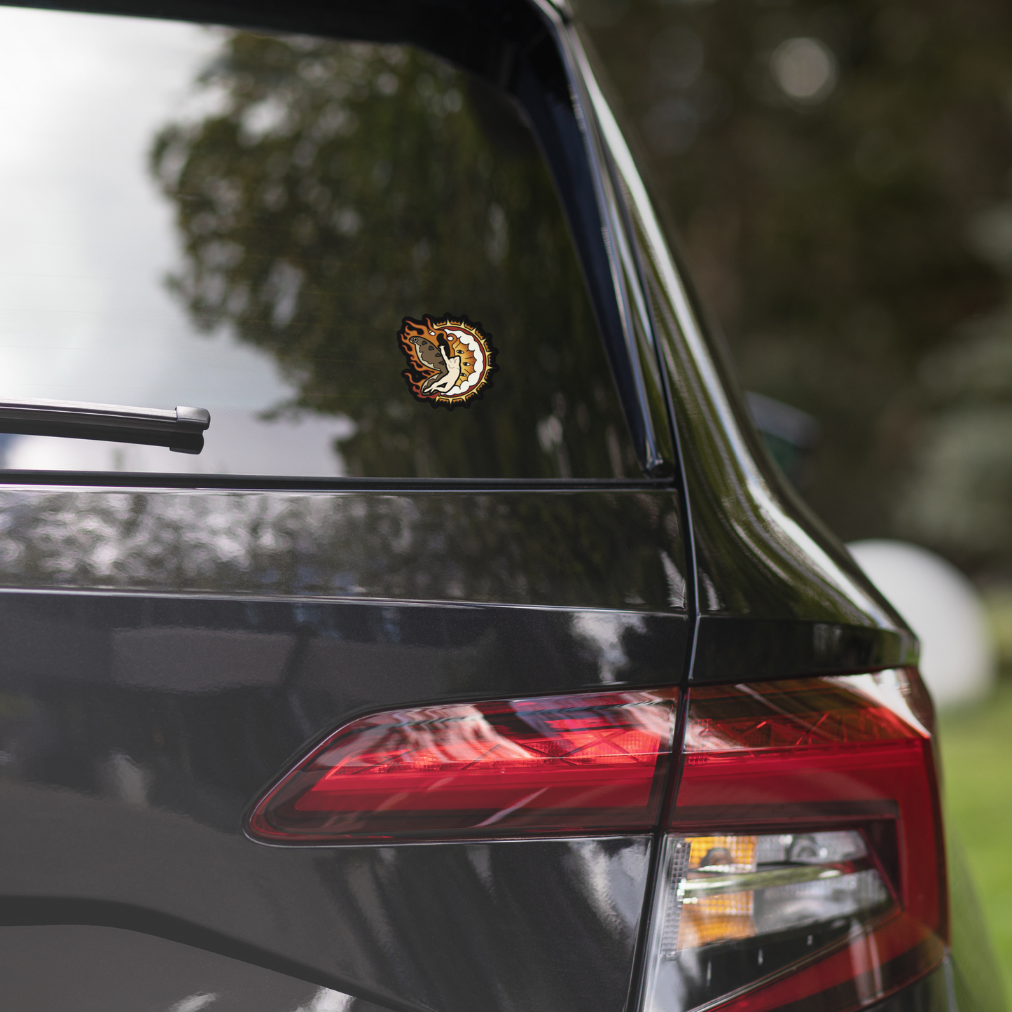 Sticker of a man with moth wings flying in front of a heavy metal biblical catholic design on a car rear windshield