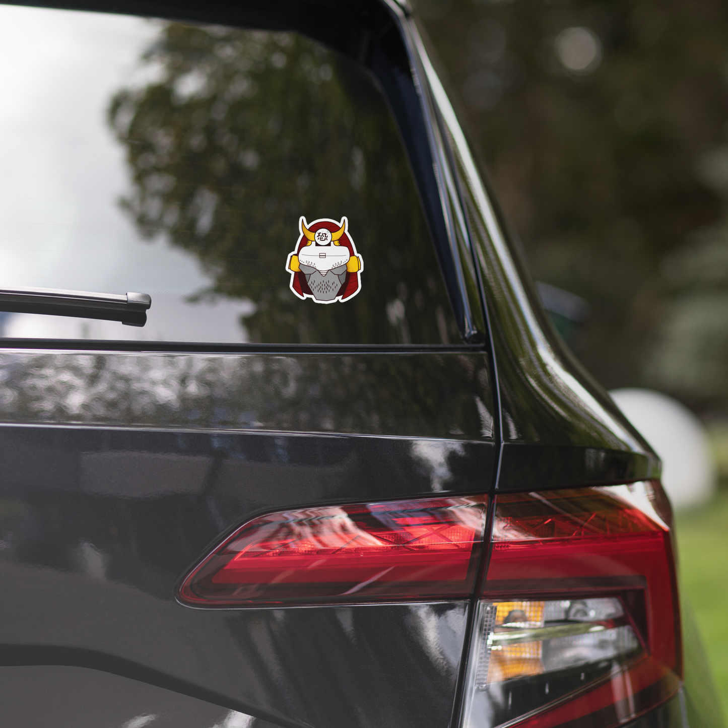 Car rear with a sticker on the window, blurred greenery in the background