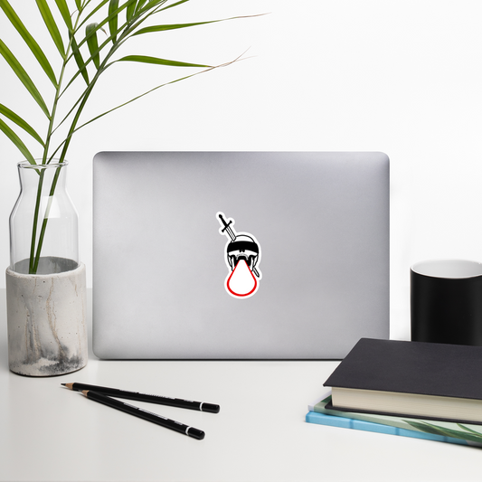 Laptop with a unique sticker on a desk with a plant, pencils, and books.