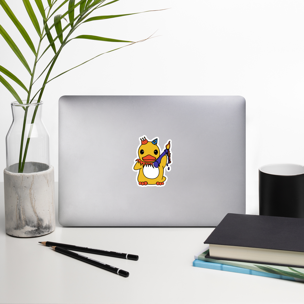 Laptop with a cartoon duck sticker on a desk with a plant, pencils, and books.