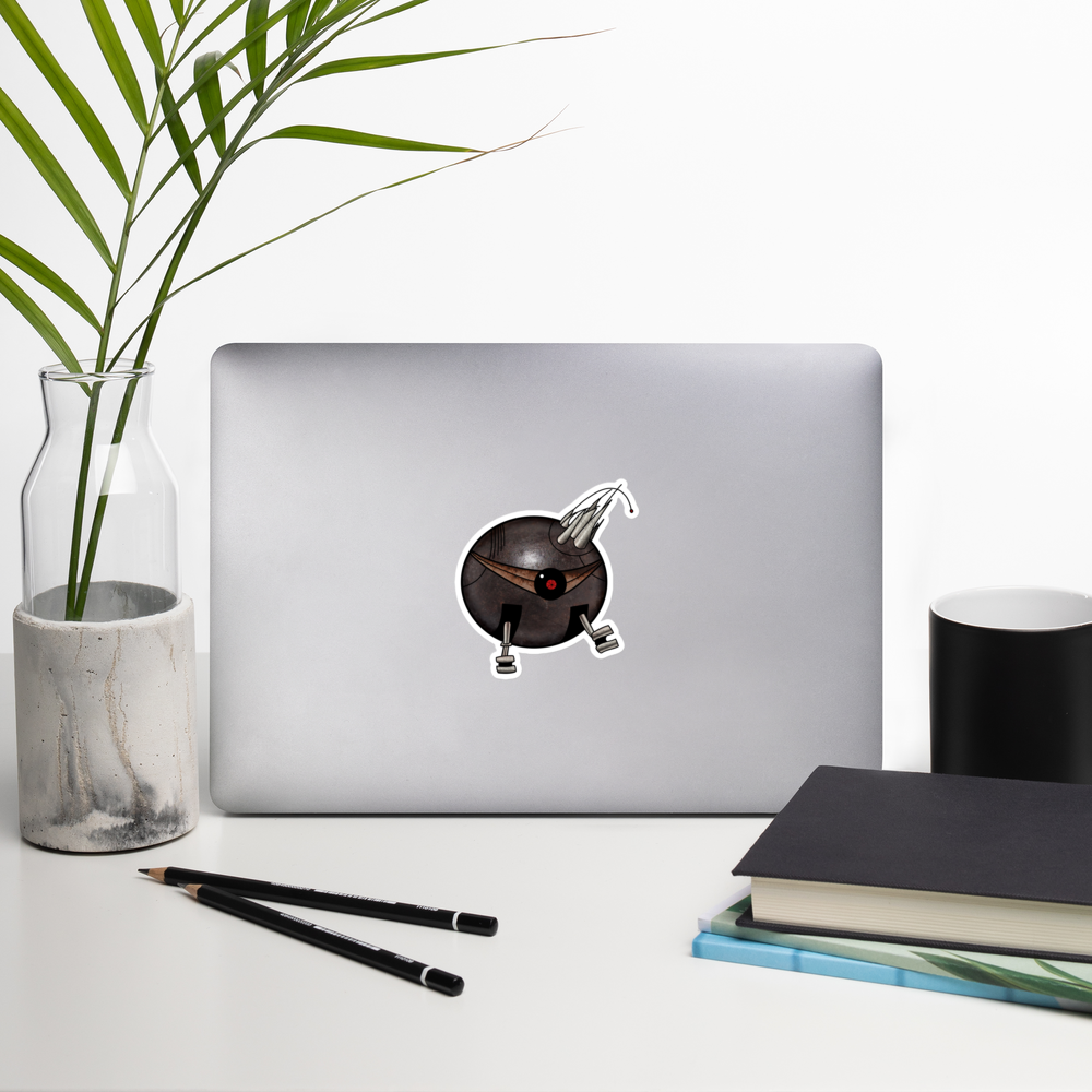 A die-cut vinyl sticker featuring a stylized, cartoonish round robot with a dark metallic gray body, a single large red and black eye, metallic silver legs, and a pair of curved metallic claws on its head, isolated on a white background on a laptop by a stack of books and a mug and a plant in a vase