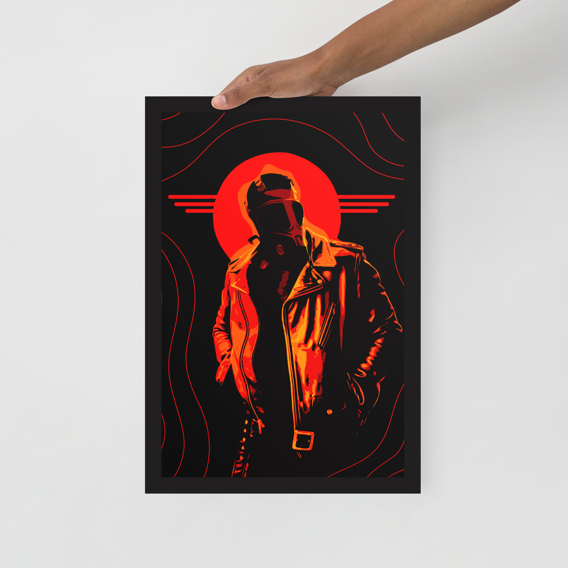 Framed artwork of a silhouette with a red circular design on a black background, held by a hand.