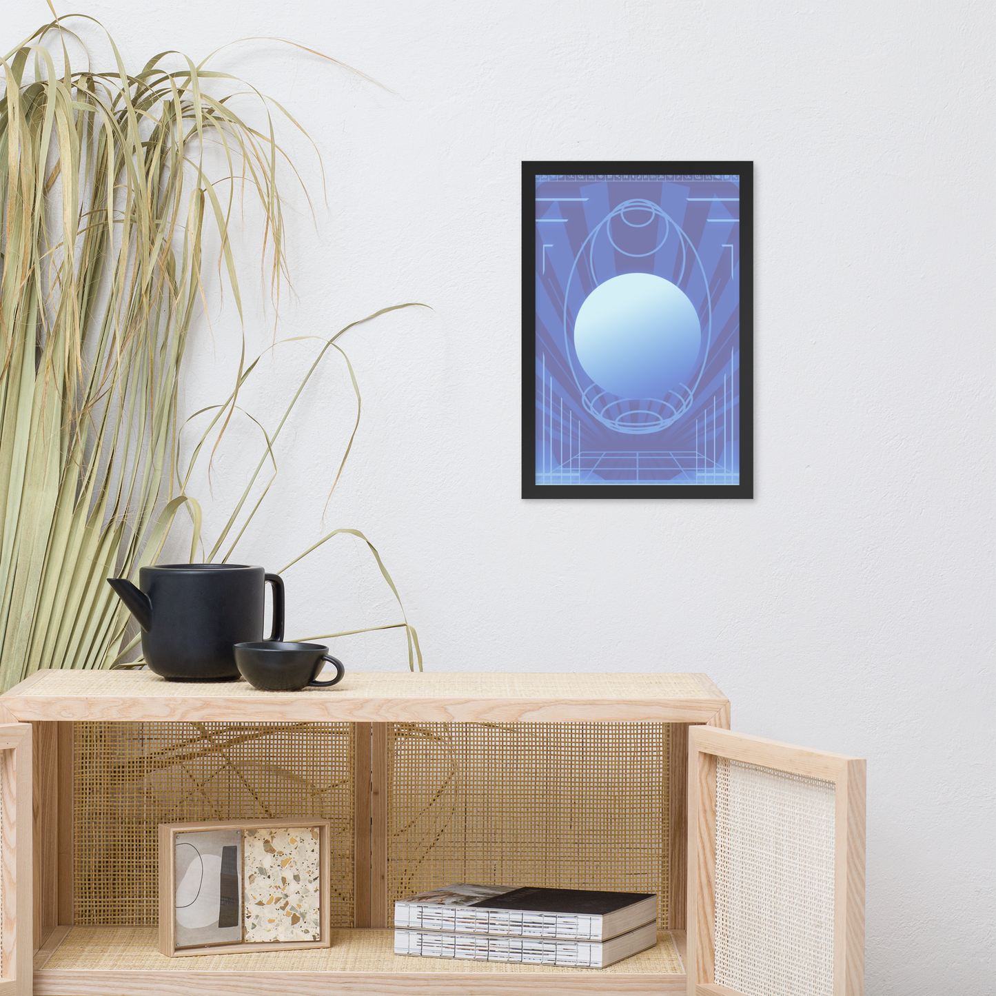 A framed abstract art print featuring a blue and purple geometric design with a central sphere, displayed on a white wall above a light wood shelf with decorative items.