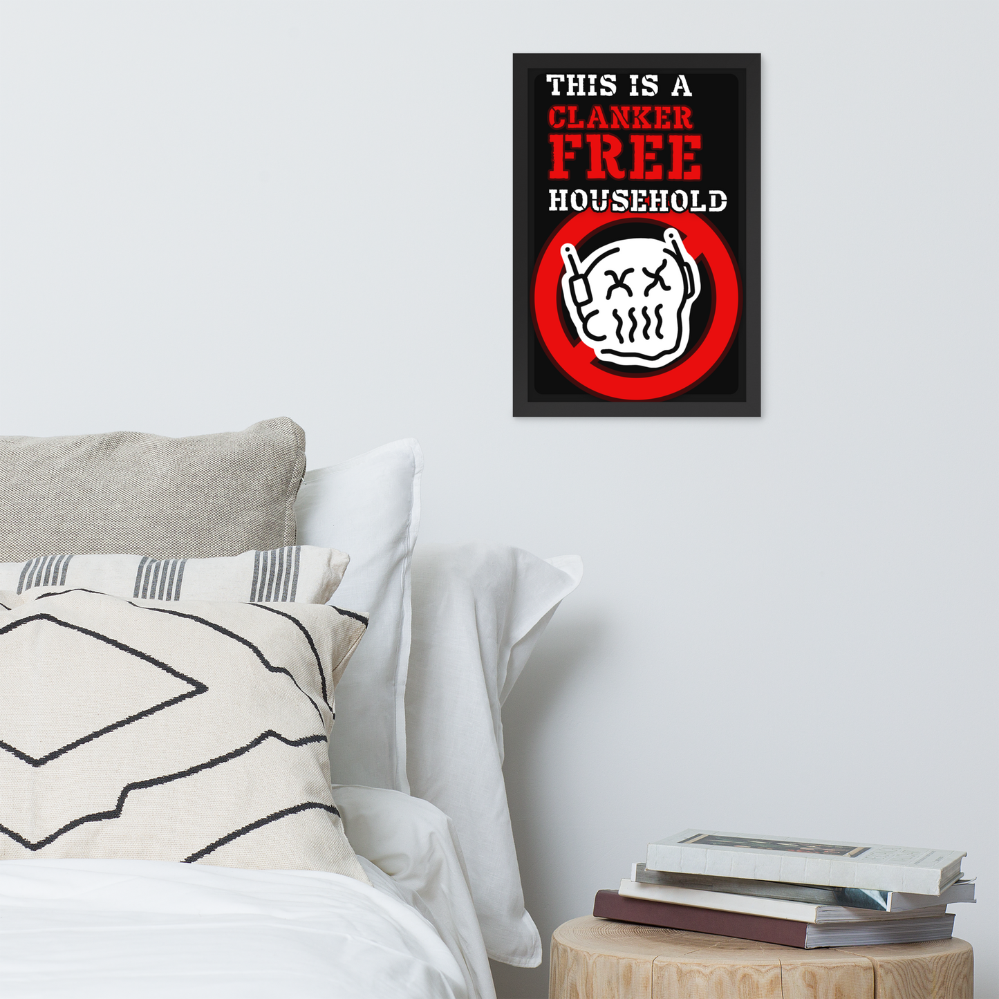 A framed wall art print with the text 'THIS IS A CLANKER FREE HOUSEHOLD' and a cartoon skull inside a red prohibition sign, displayed above a bed in a styled bedroom scene.