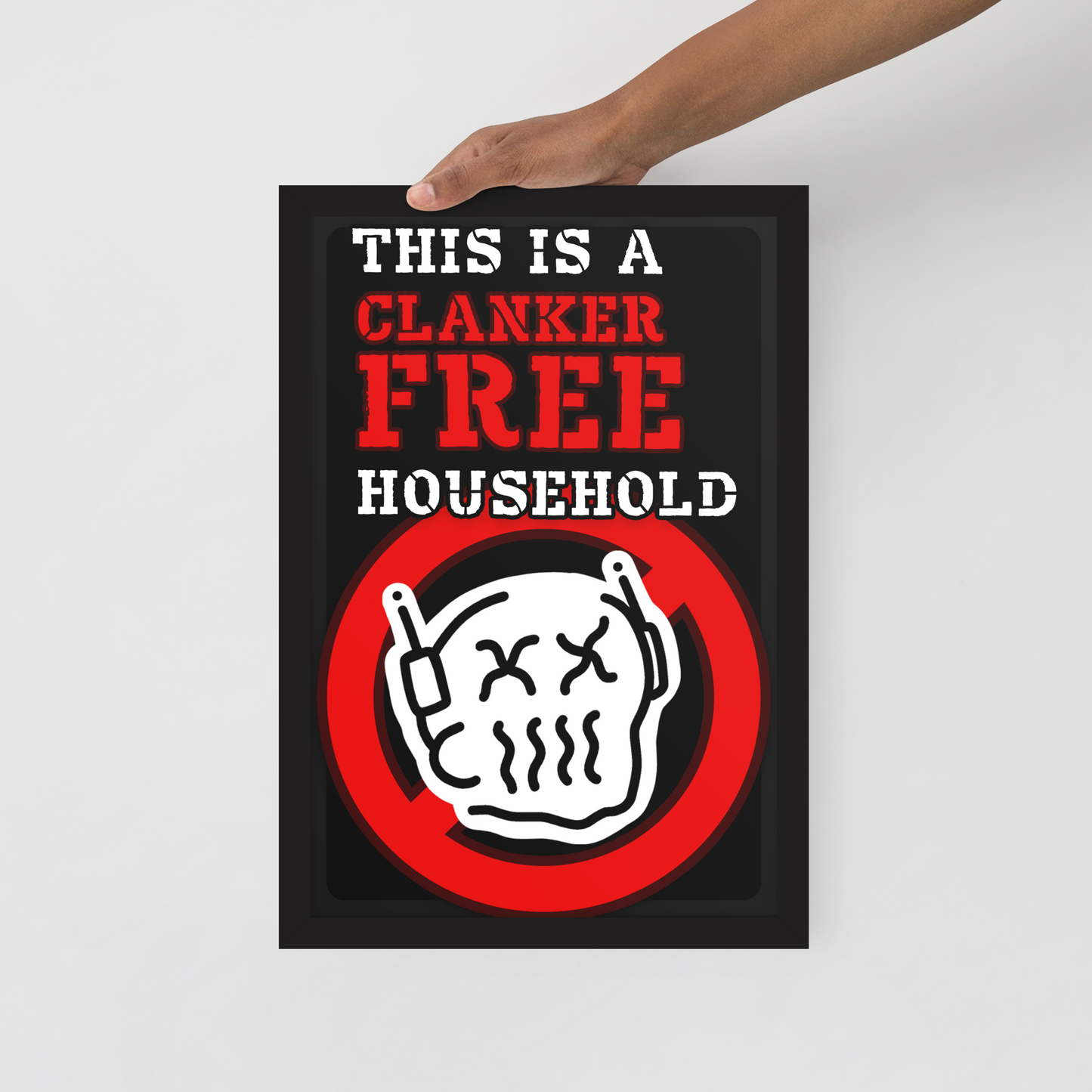 A hand holds a black poster with the text 'THIS IS A CLANKER FREE HOUSEHOLD' in white and red, above a white skull icon inside a red prohibition circle, against a light gray background.