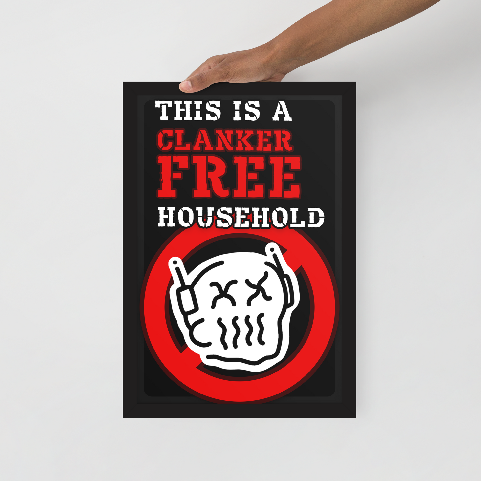 A hand holds a black poster with the text 'THIS IS A CLANKER FREE HOUSEHOLD' in white and red, above a white skull icon inside a red prohibition circle, against a light gray background.