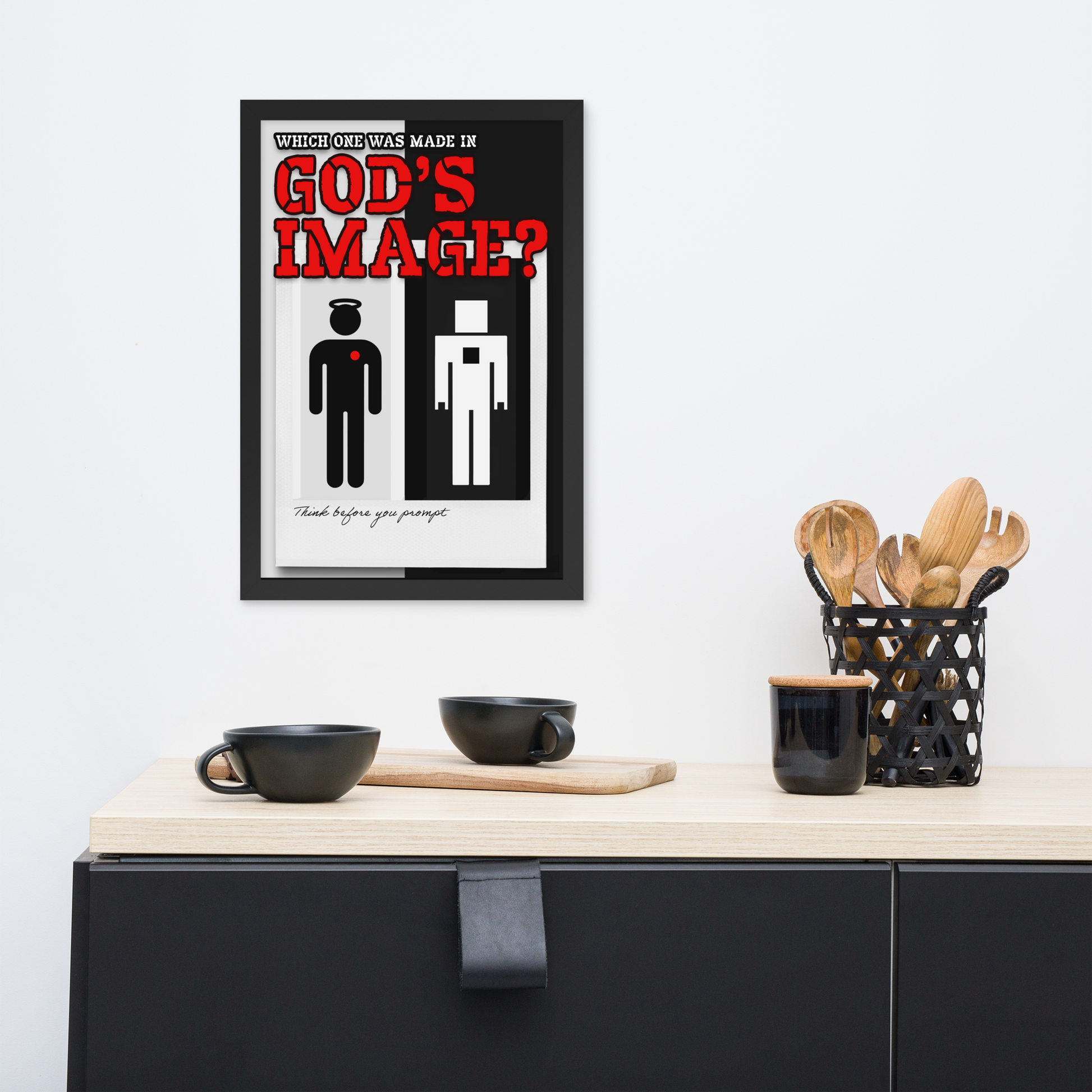A framed minimalist art print hanging on a white wall above a kitchen counter. The print features the text 'WHICH ONE WAS MADE IN GOD'S IMAGE?' with a black and white figure design and red lettering.