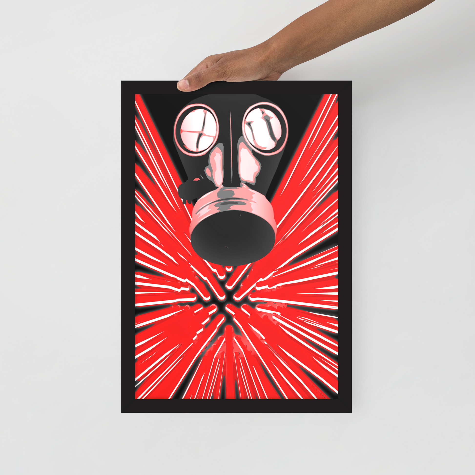 A framed art print featuring a stylized gas mask over a red and black burst pattern, held by a person's hand against a light gray background.