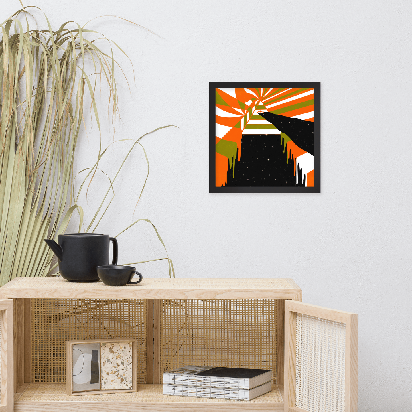 Abstract framed artwork on a wall above a wooden shelf with decor items.