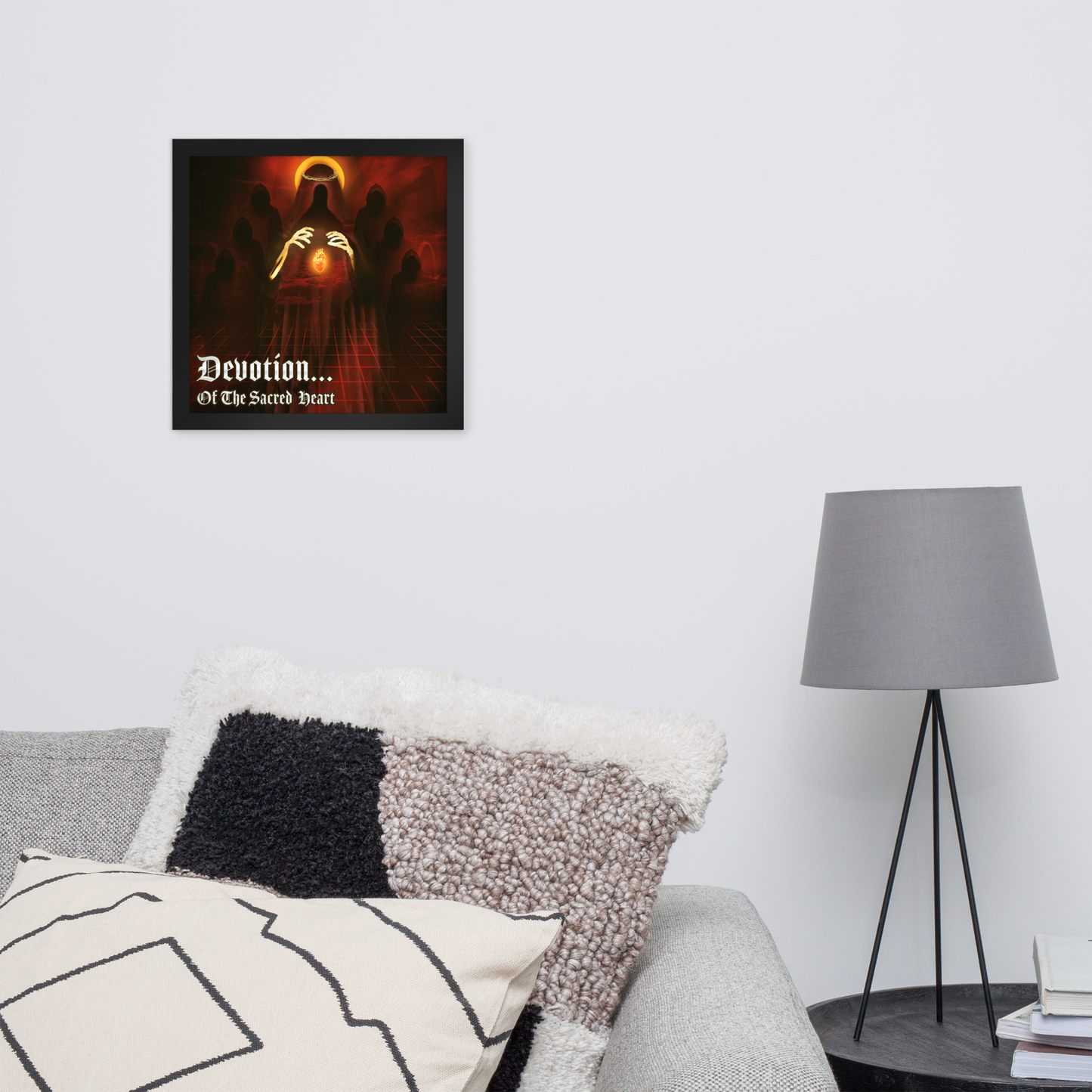 Framed artwork titled 'Devotion... Of The Sacred Heart' above a couch in a living room area with a lamp