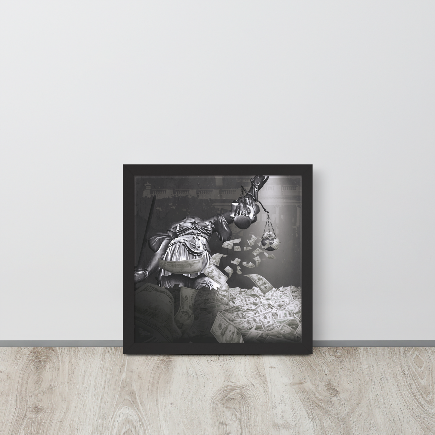 Framed black and white artwork of a person with a baby on a wooden floor against a light gray wall.