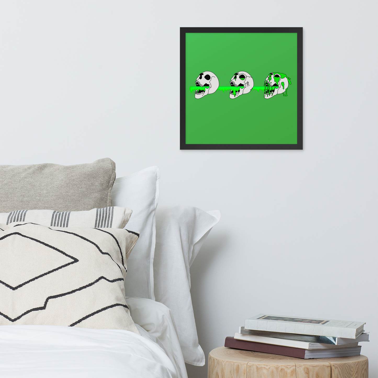 Framed artwork of 3 skulls shooting green slime from their mouths with a gradient background in a horror style above a bed.