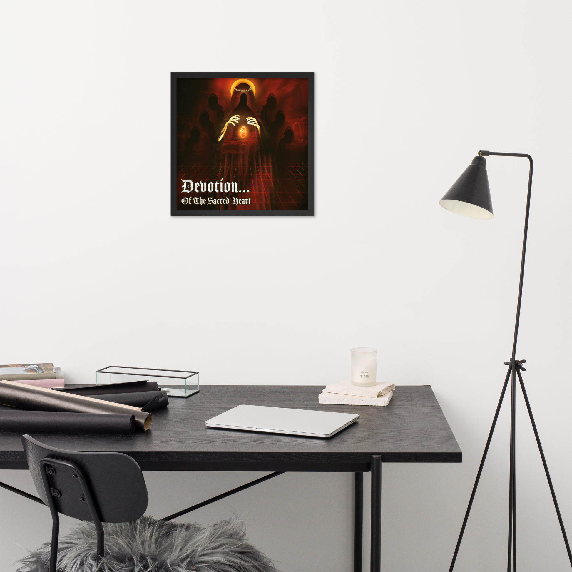 Framed artwork above a desk with a lamp and books in a room setting