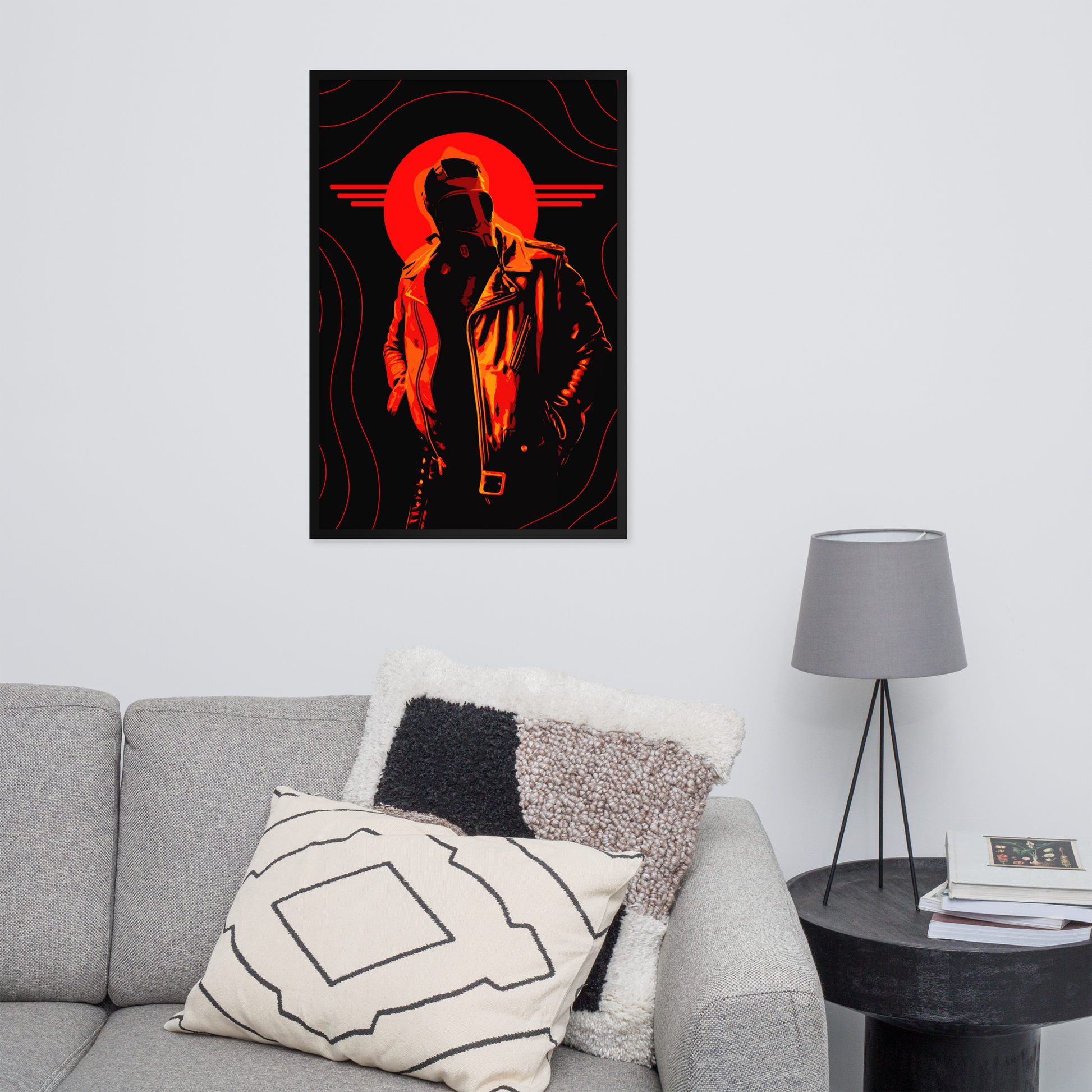 Poster of a silhouette with a red circle on a wall above a gray sofa with decorative pillows.