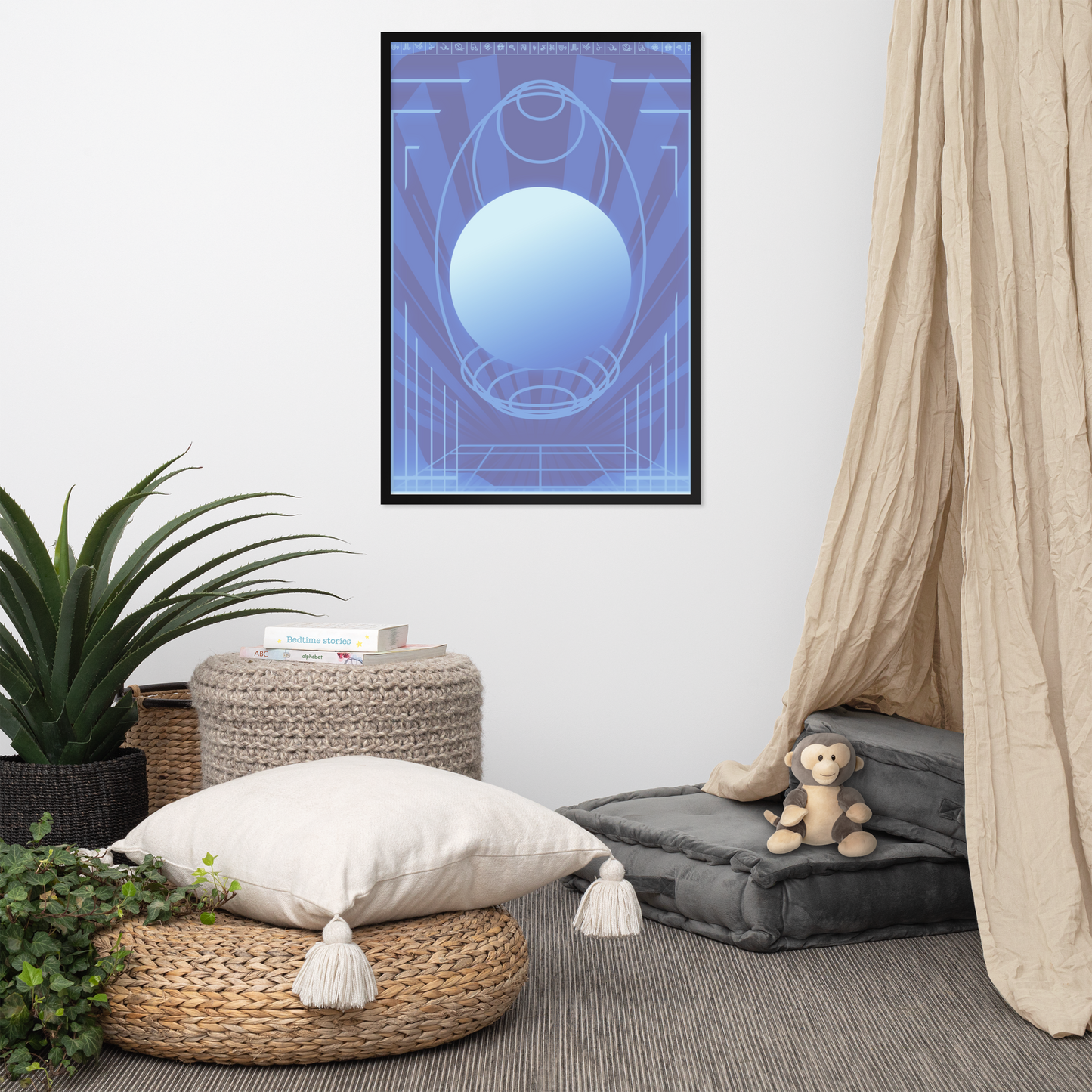 A framed wall art print featuring a blue and light blue geometric design hangs on a white wall in a styled room with a beige canopy, woven ottomans, a potted plant, and a small stuffed monkey.