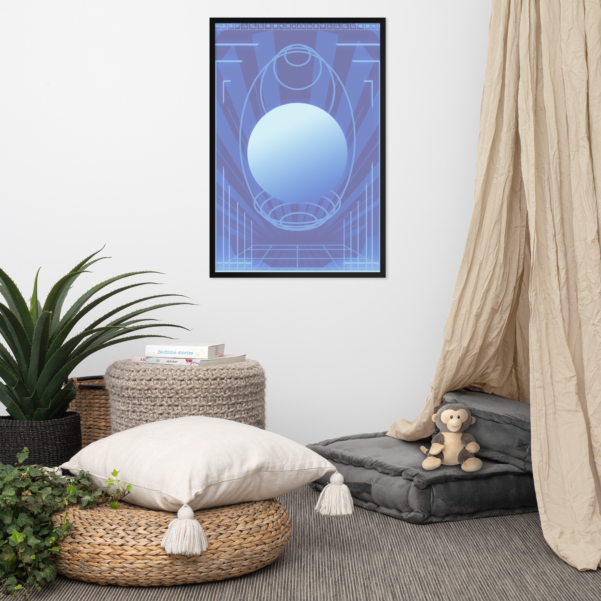 A framed wall art print featuring a blue and light blue geometric design hangs on a white wall in a styled room with a beige canopy, woven ottomans, a potted plant, and a small stuffed monkey.